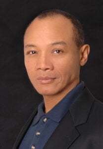 Professional acting headshots: A theatrical studio headshot of actor Paul Calderón in a dark suit against a black background.
